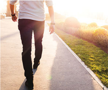 Man walking on a sidewalk on a bright sunny day