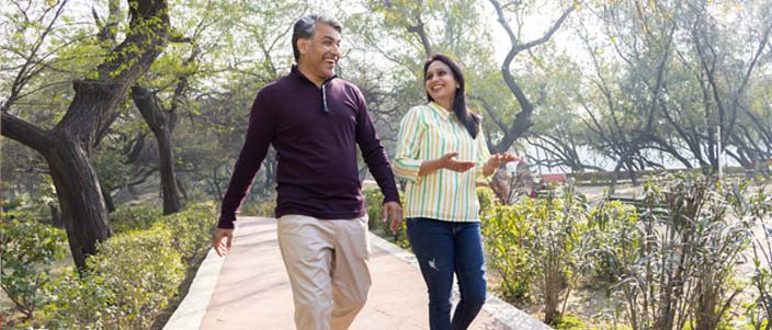 Man and woman walk through forest on a sunny day