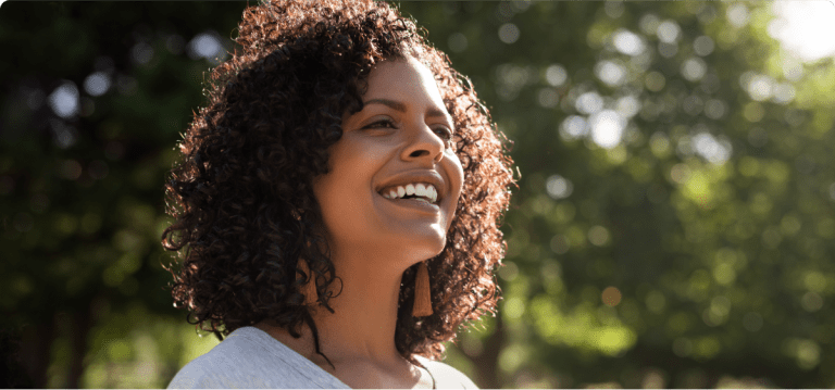 Smiling woman takes a walk outside in the sunshine.