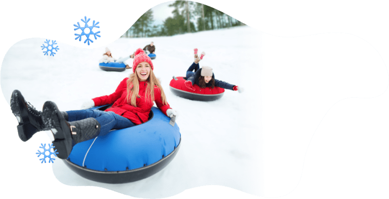 Friends sledding downhill on tubes smiling and laughing